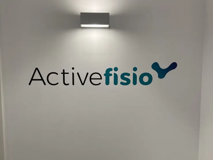 El logo de Activefisio en la pared de la recepción, bajo un aplique
