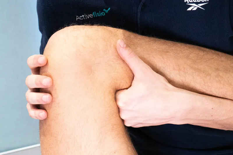Un fisioterapeuta explora con las dos manos una rodilla flexionada